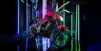 Perspectiva Lateral Direita da Moto Honda CB 300F Twister na cor Vermelho Estacionada Em Rua Estreita Com Fundo Iluminado e Futurista 26