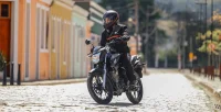 Perspectiva lateral com Motociclista pilotando e em movimento de curva a Moto Honda CG 160 Titan Cinza Metálico 11