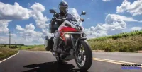 Homem Pilotando Moto Honda NC 750X em Estrada de Asfalto com Céu Azul ao Fundo 30