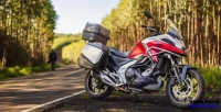 Lateral Direita da Moto NC 750X Vermelha com Homem ao Fundo Desfocado 25