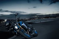 foto action da nova GSX-S1000 com a cidade ao fundo e o céu anoitecendo 3