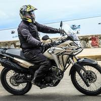 Honda Sahara 300: Trail aventureira, bege, pilotagem em estrada costeira